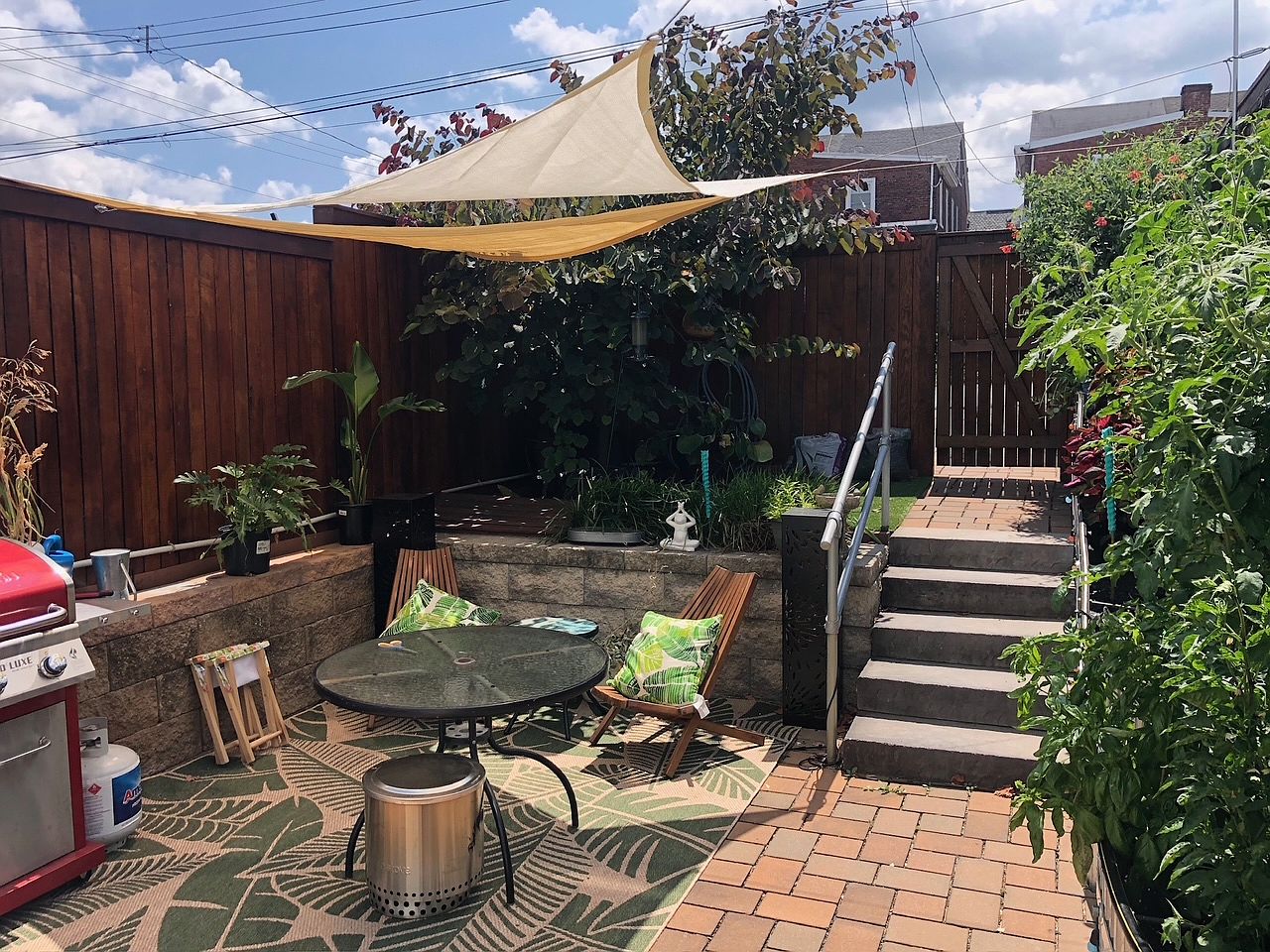 Garden patio at 304 Grove Street, with planted borders, seating, and shade sails